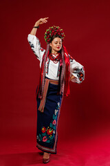 Portrait of ukrainian woman in traditional ethnic clothing and floral red wreath on viva magenta studio background. Ukrainian national embroidered dress call vyshyvanka. Pray for Ukraine