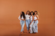 © Flamingo Images - Diverse women in white tops and jeans standing on an orange background