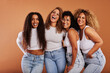© Flamingo Images - Diverse women in white tops and jeans laughing on an orange backdrop
