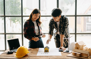 Wall Mural - Two colleagues discussing data working and tablet, laptop with on on architectural project at construction site at desk in office