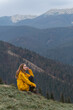 © somemeans - Girl sits on side of the mountain. Portrait of young happy woman in mountains enjoying clean air. Vertical view.