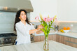 Happy woman putting flowers on a granite countertop in the kitchen