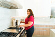 Hispanic overweight woman cooking dinner on the stove