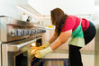 Overweight woman baking cookies in a stainless steel oven