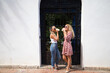 © @skuder_photographer - Two beautiful women having a drink while strolling through the streets of a mediterranean style city center in spain. The women are having fun. Vacation and travel concept.