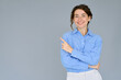 © insta_photos - Happy young smiling professional business woman wearing blue shirt looking at camera pointing finger away at copy space showing aside presenting advertising offer standing isolated at gray background.