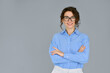 © insta_photos - Happy young smiling confident professional business woman wearing blue shirt and glasses, happy pretty female executive looking at camera, standing arms crossed isolated at gray background, portrait.
