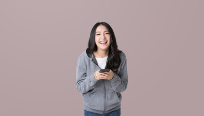 Wall Mural - Asian woman Holding the phone smiling happily while looking at the camera on isolated brown background