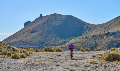 nice senior woman cycling with her electric mountain bike in the volcanic nature park of Cabo de Gata, Costa del Sol, Andalusia, Spain