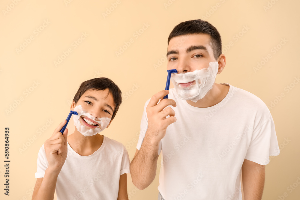 Father and his little son shaving against beige background