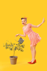 Poster - Young pin-up woman with watering can and houseplant on yellow background