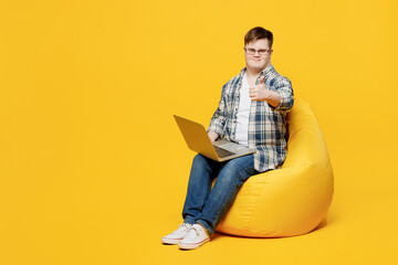 full body young it man with down syndrome wear glasses casual clothes sit in bag chair work hold use