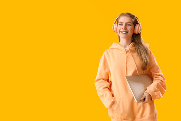 Female programmer in headphones with laptop on yellow background