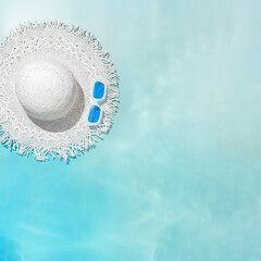 Wall Mural - Summer flat lay white sun hat and colored sunglasses at sunshine on blue teal gradient background. Creative aesthetic Life style summer sea holidays photo, top view, abstract water texture