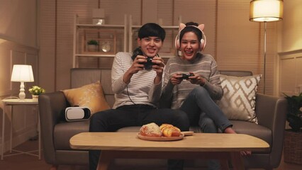 Wall Mural - Young asian couple family playing online video games at home.