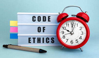 Poster - text code of ethics written on the lightbox with alarm clock and colorfull stickers on blue backgrou