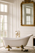 Free-standing bathtub near the window with gold faucets and vintage mirror
