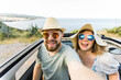 © satura_ - Happy beautiful couple in love taking a selfie portrait driving a convertible car on the road at vacation. Rental cars and vacation