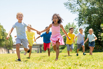 Cheerful kids are jogging together in the park and having fun