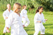 Barefoot kids doing kata during outdoor karate training.