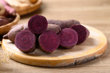 Wall Mural - Organic purple sweet potatoes on cutting wooden board