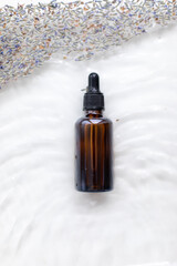 Wall Mural - Amber bottle of lavender essential oil. Flat lay concept. Light background with water waves.