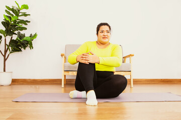 Wall Mural - Asian fat woman wearing yellow sportswear at home light fitness exercises sit on a yoga mat flex your knees Keep your balance and relax take time to take care of your health : Health care concept.