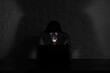 © alexkich - Hacker in black mask and hood at the table