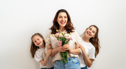daughters giving mother bouquet of flowers.