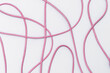 Poplątana  różowa linka tworząca wzór na białym tle