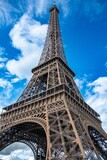 Fototapeta Paryż - Vertical low angle shot of the Eiffel Tower against a blue cloudy sky in Paris, France