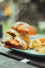 Sticker - Vertical shot of a burger with chicken and cheese served with potatoes