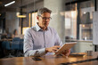 © JustLife - Portrait of businessman in office. Man using digital tablet. Businessman having video call.