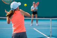 A Girl Plays Tennis On A Court With A Hard Blue Surface On A Summer Sunny Day