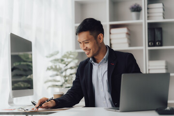 Happy working asian businessman talking on the phone with accounting documents at desk in happy working office