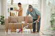 © DragonImages - Senior woman vacuum cleaning floor when husband wiping dust
