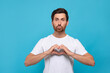 © New Africa - Handsome man making heart with hands and blowing kiss on light blue background