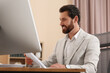 © New Africa - Happy businessman working with documents at table in office