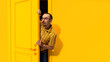 Young man in glasses peeking out yellow door and looking with excitement, shock and positive impression. Big sales, success, win. Concept of emotions, facial expression, lifestyle, sales
