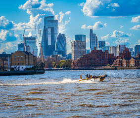 A speed boat on the Thames with central London buildings in the background 