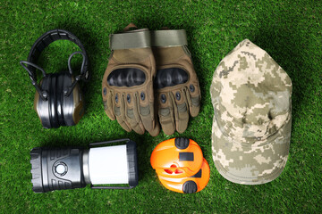 Different military training equipment on green grass, flat lay