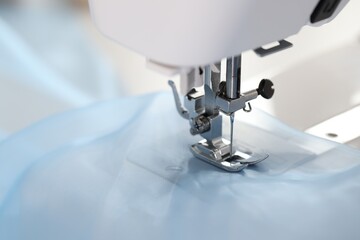 Sewing machine with light blue fabric, closeup