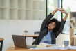 © ArLawKa - Young african american businesswoman relaxing with hands at office tired employee sitting at desk feeling tired back muscle tension after work