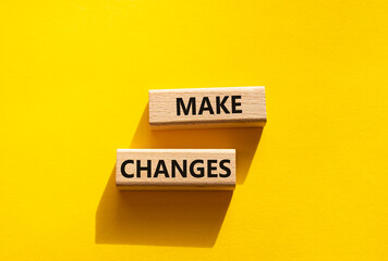 Wall Mural - Make changes symbol. Wooden blocks with words Make changes. Beautiful yellow background. Business and Make changes concept. Copy space.