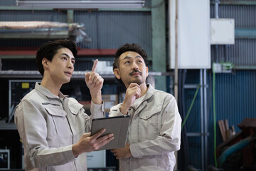 Wall Mural - Workers looking up from their tablets to check processes and safety at factories and job sites.