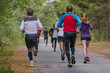 © sports photos - group runners male and female running race on park road, autumn marathon, fallen yellow leaves on ground