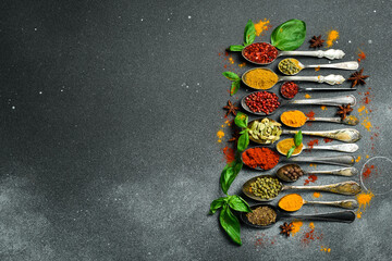 Set of spices and herbs in vintage spoons. Colorful various spices for cooking. On a black slate background.