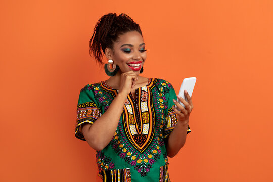 Wall Mural - Stylish african woman in traditional costume using smartphone