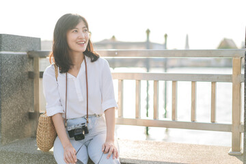 Young beautiful asian woman traveler sitting by the river at sunny day