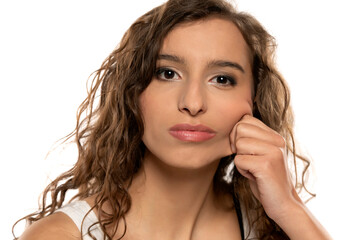 Portrait of young cyrly brunette woman, pulling her cheek skin  on white background